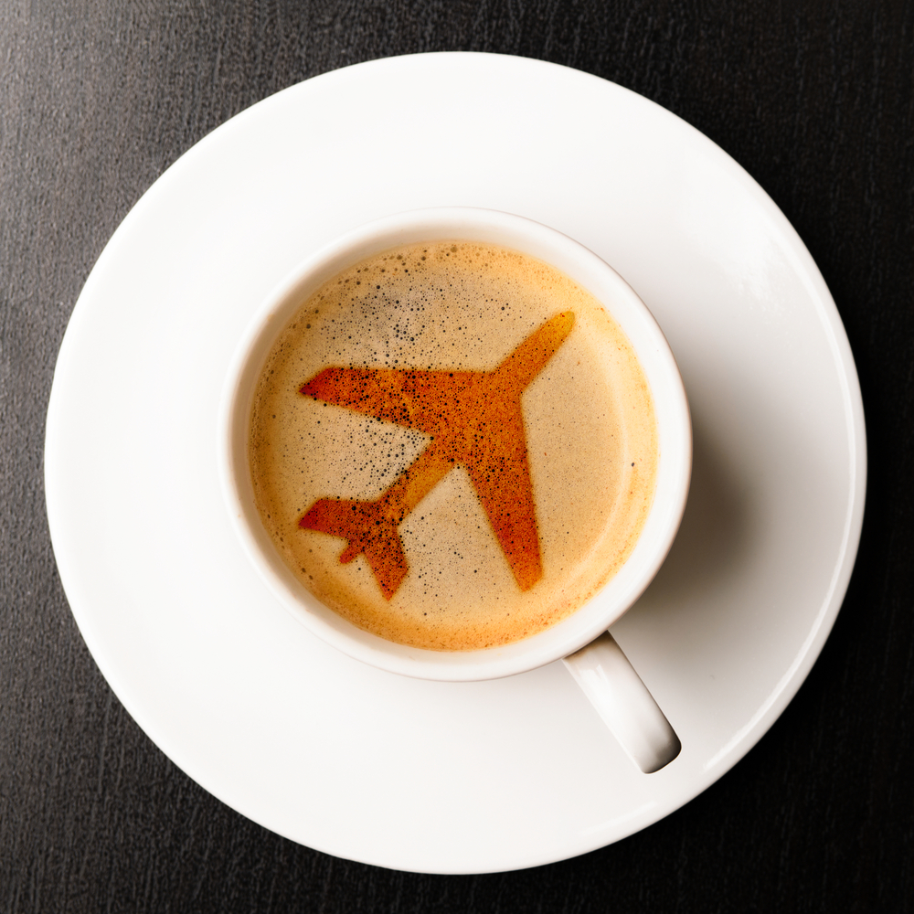 a cup of coffee with a drawing of an airplane on the foam