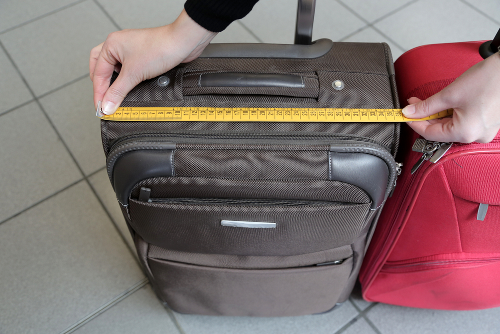 a hand measuring a suitcase