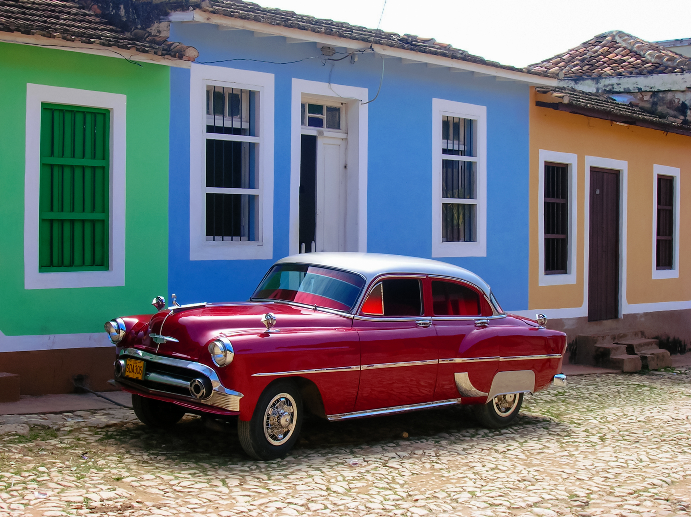 a red car parked in front of a colorful building