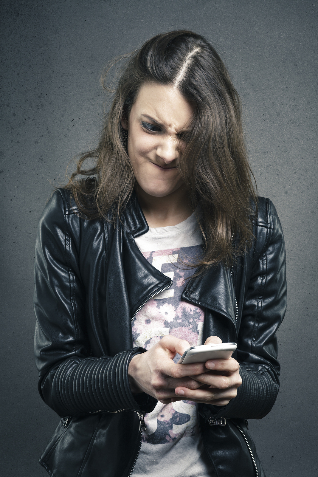 a woman in a leather jacket looking at a cell phone