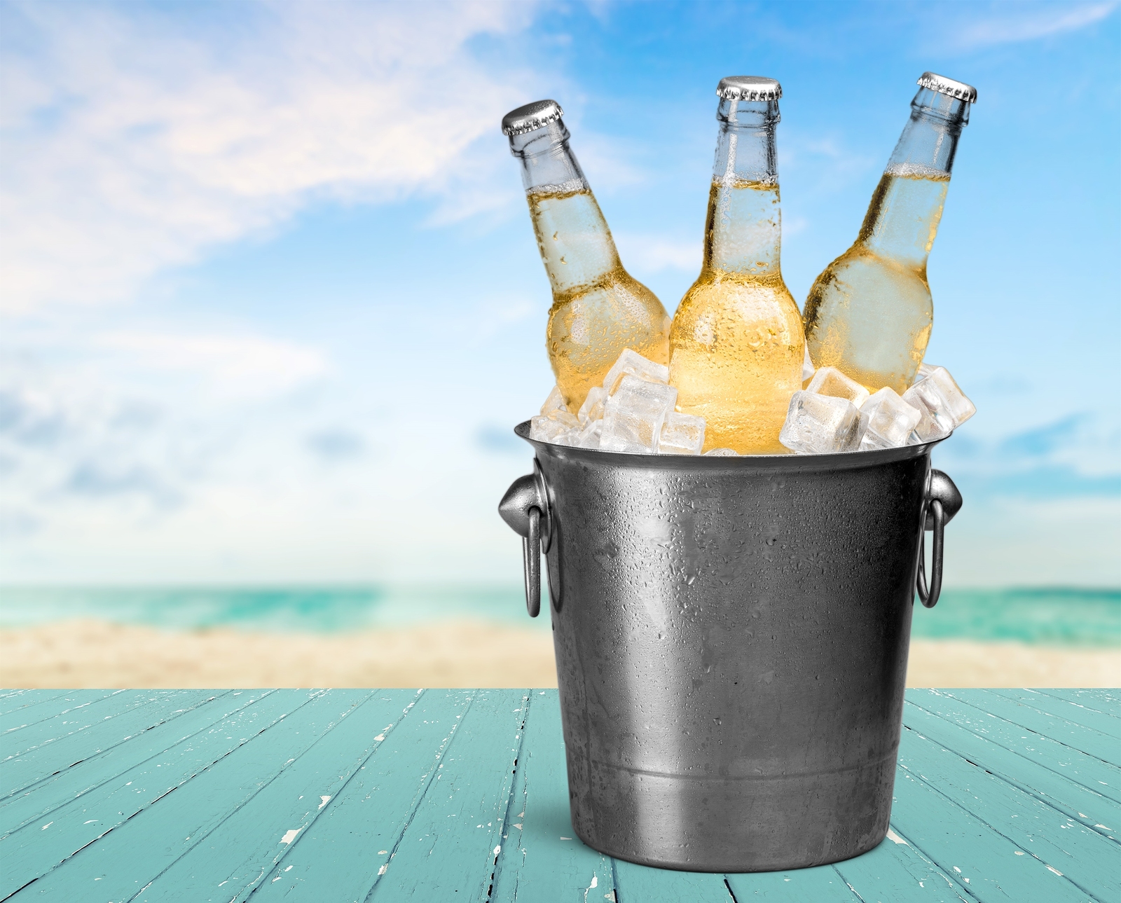a bucket of beer with ice on a blue surface