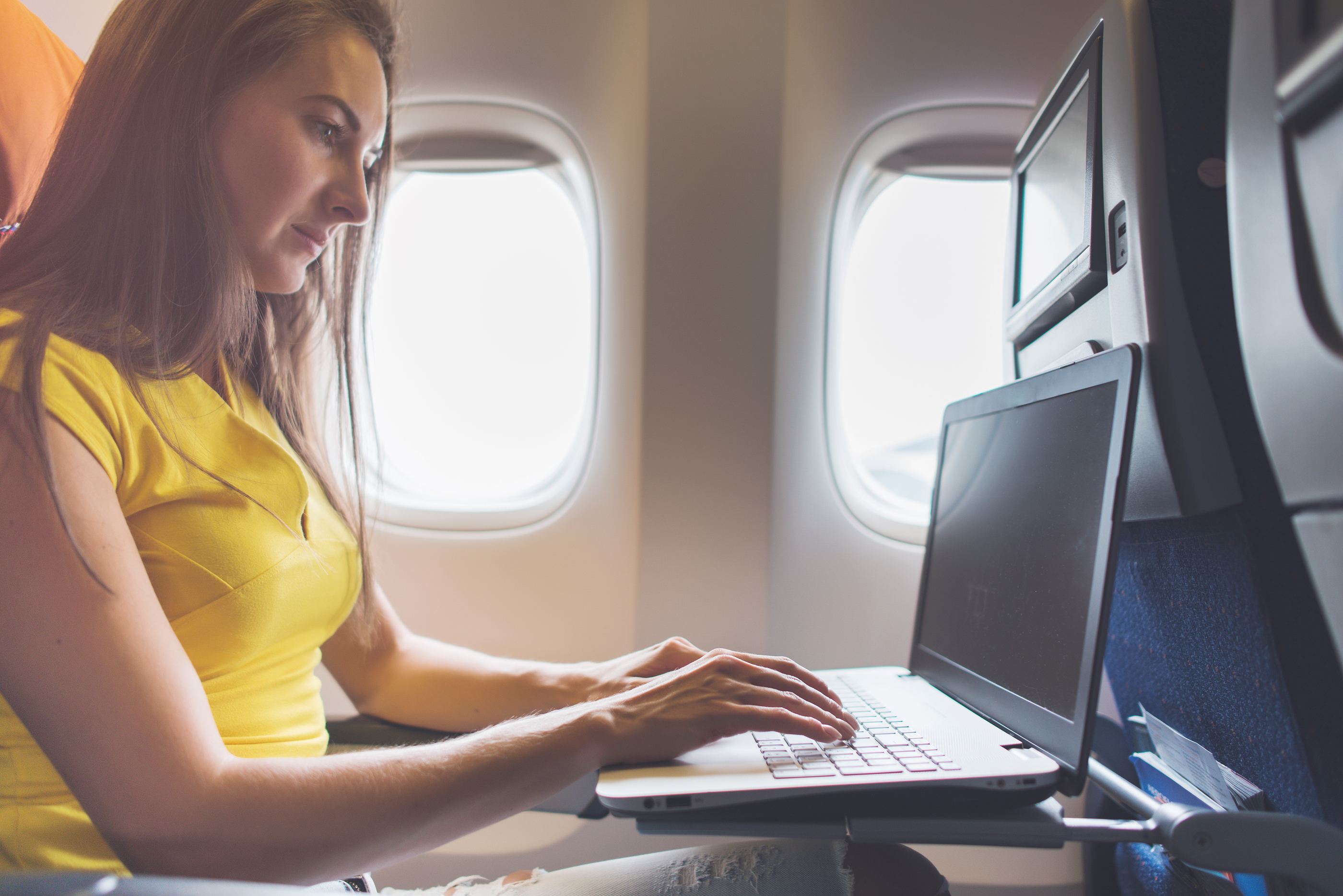 a woman sitting in an airplane using a laptop