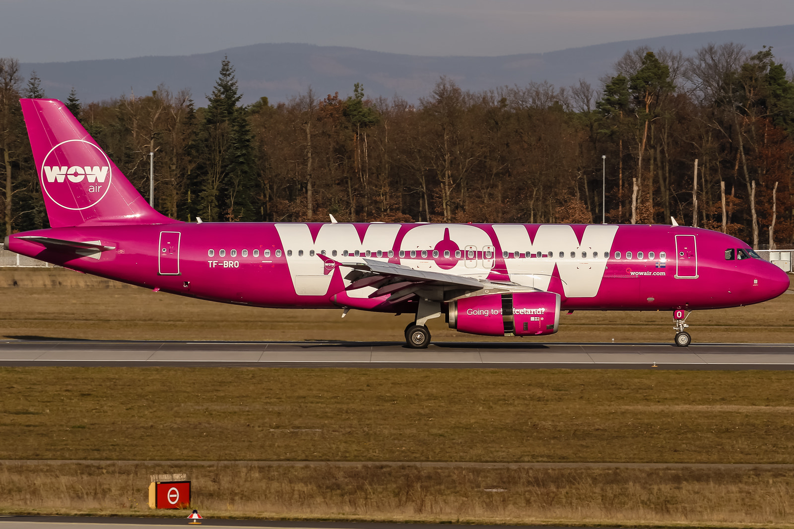 a pink and white airplane on a runway