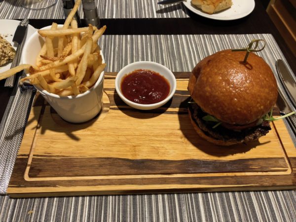 a burger and fries on a wooden board