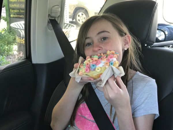 a girl eating a pastry in a car
