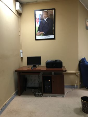 a desk with a computer and a picture on the wall