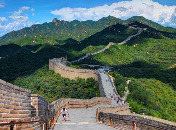 a long wall with people walking on it with Great Wall of China in the background