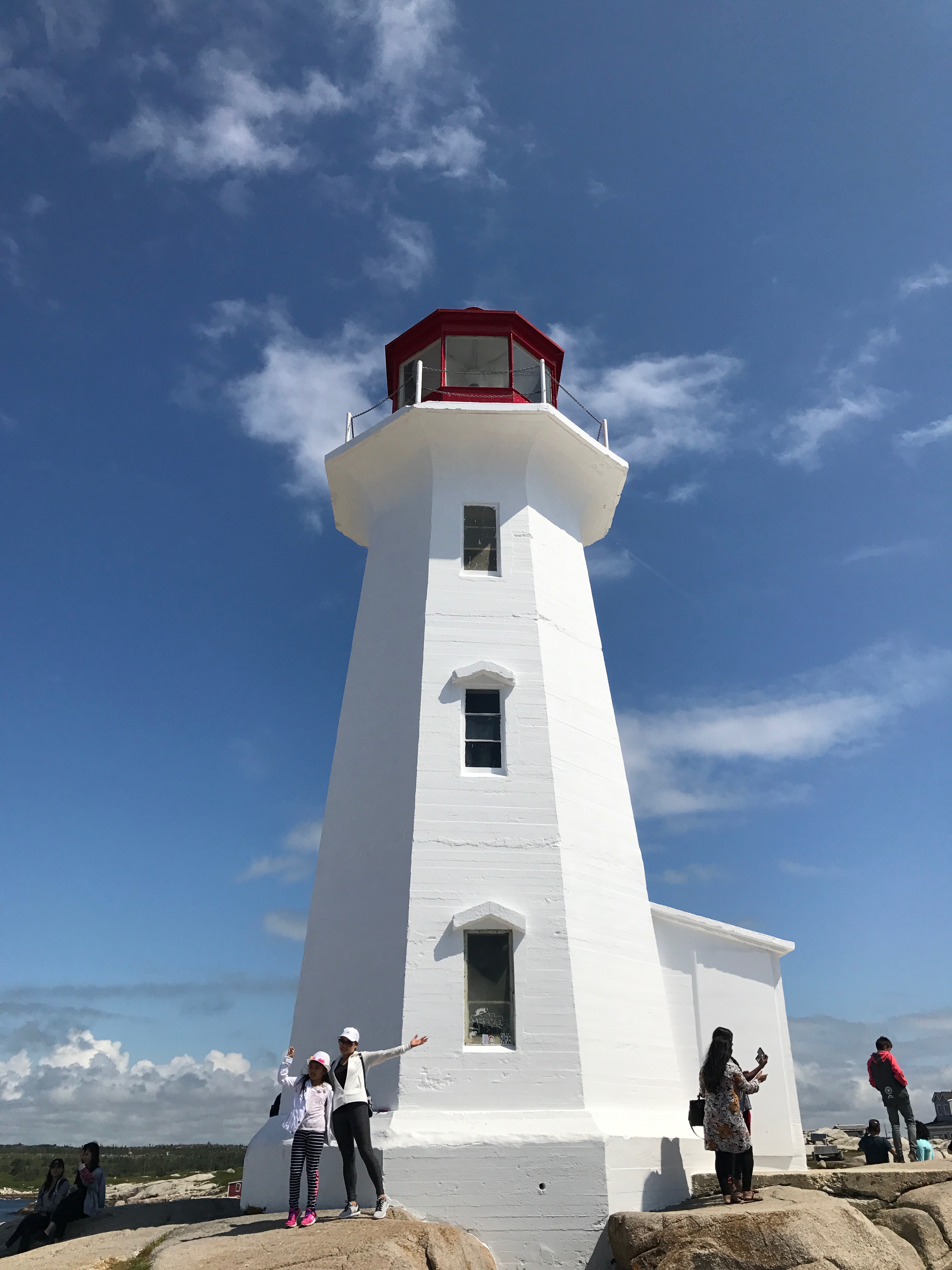 a white lighthouse with people standing on the ground