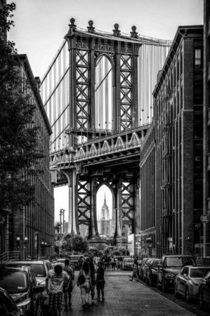 Manhattan Bridge with a large arch and people walking on the street