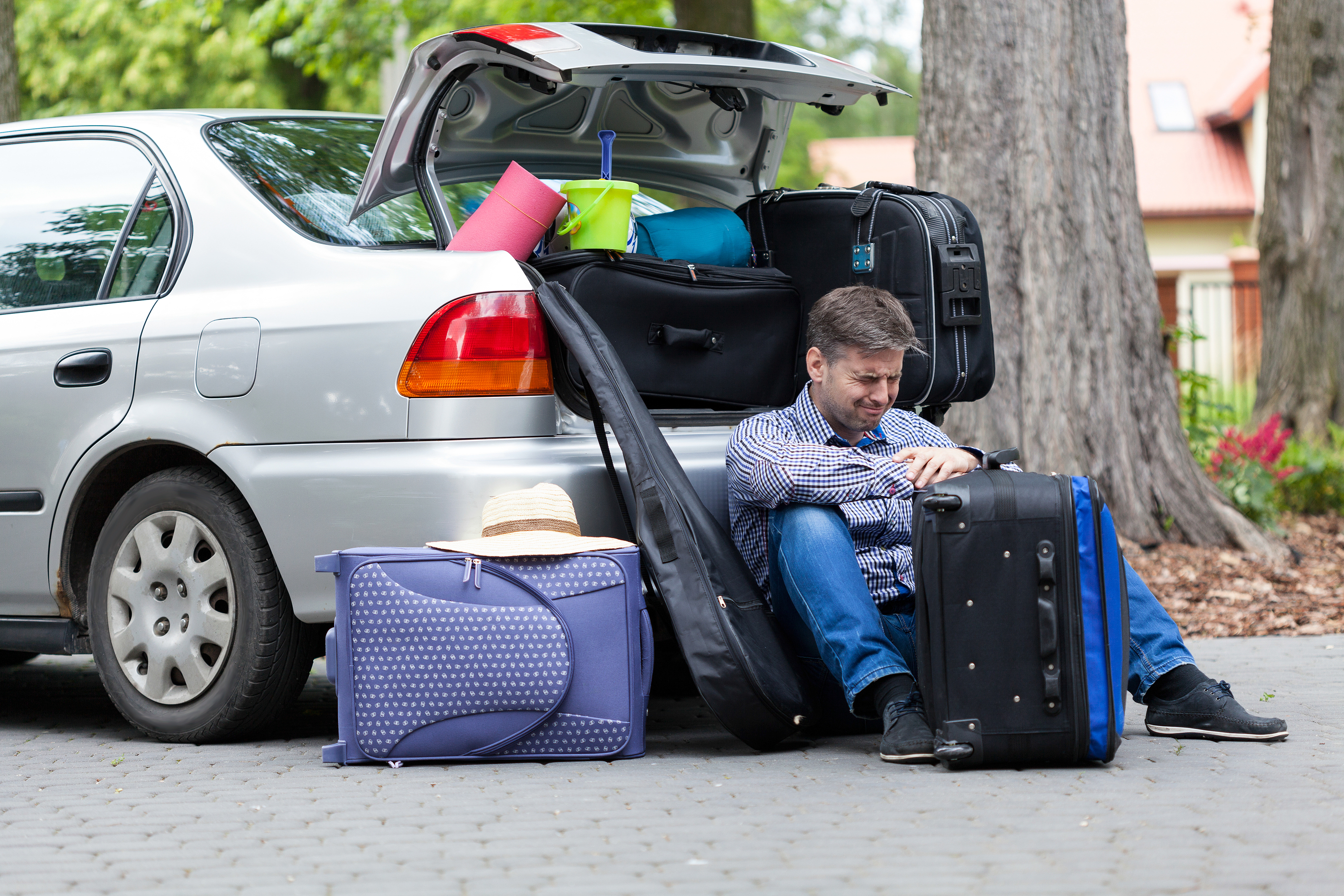 a man sitting in the trunk of a car with luggage
