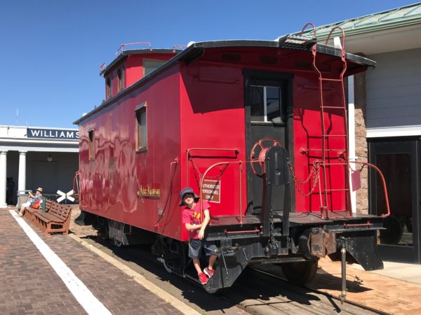 a child standing in front of a red train