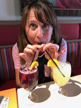 a woman drinking from straws next to a pair of drinks