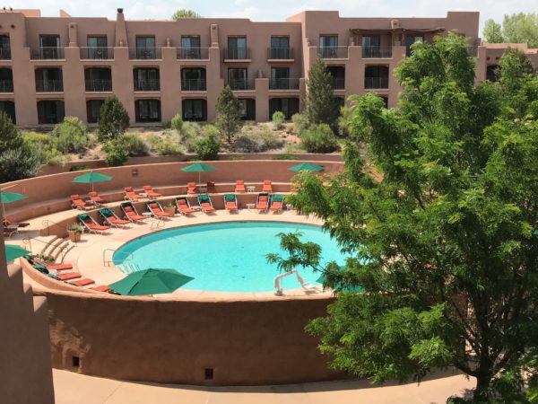 a pool with umbrellas and chairs in a courtyard