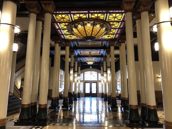 a large hallway with columns and a stained glass light fixture