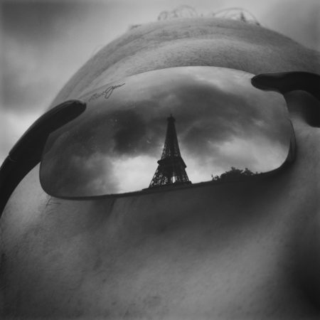a person wearing sunglasses with a tower reflected in them
