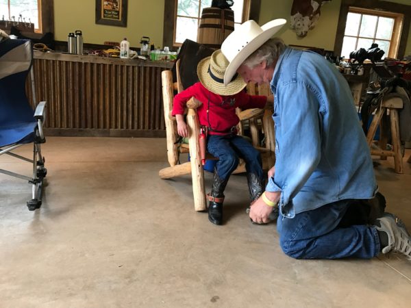 a man kneeling on a chair with a child in a cowboy hat