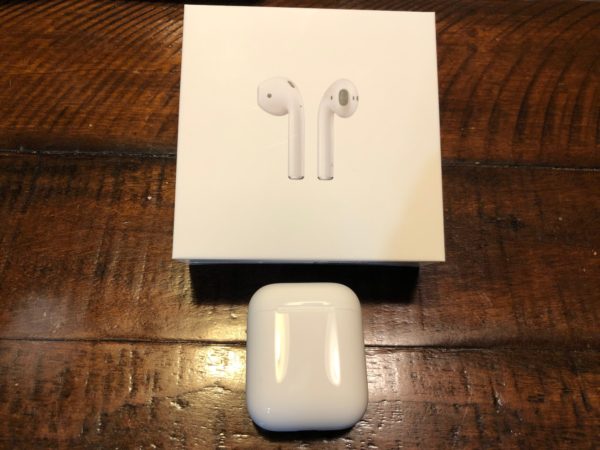 a box and box with a white box and a white earbud on a wooden surface