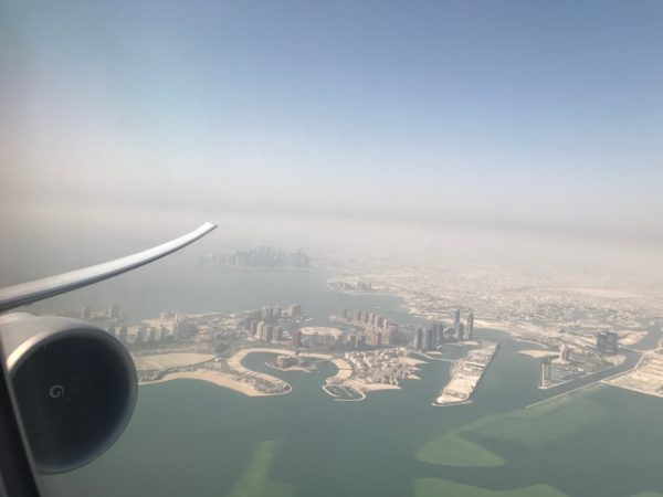 an airplane wing and water with buildings and a city