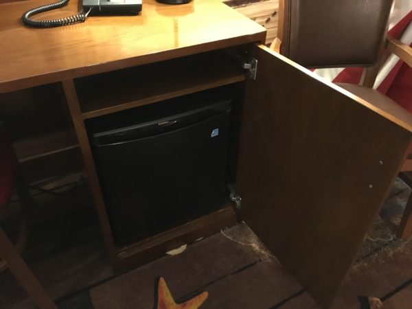 a small black refrigerator under a desk