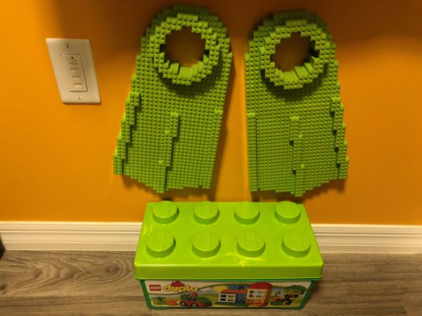 a green plastic blocks on a yellow wall