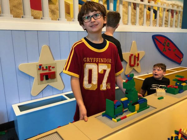 a boy standing in front of a counter with lego blocks