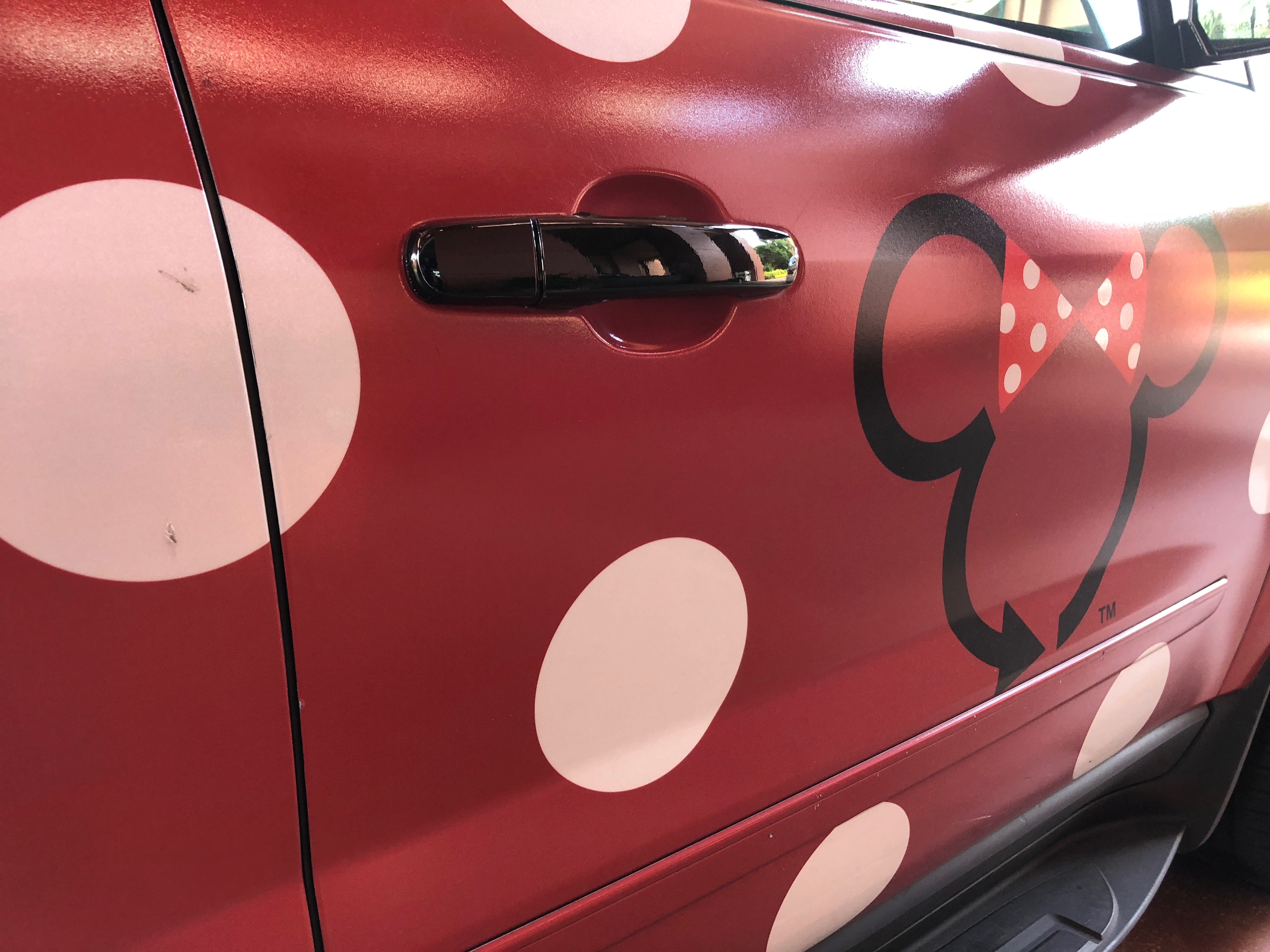 a red car with white polka dots and a cartoon mouse