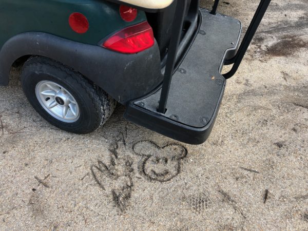 a golf cart with a mouse face drawn in the sand