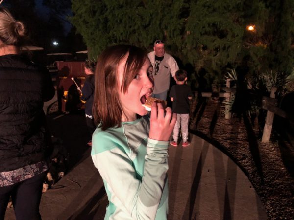 a woman eating food outside at night