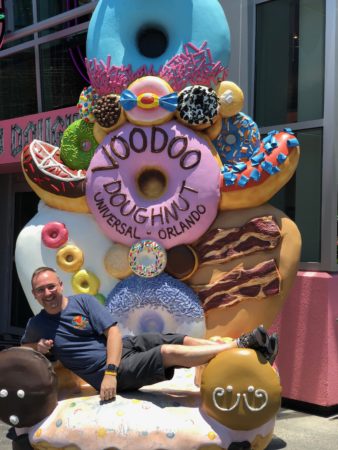 a man lying on a bench with a large doughnut statue