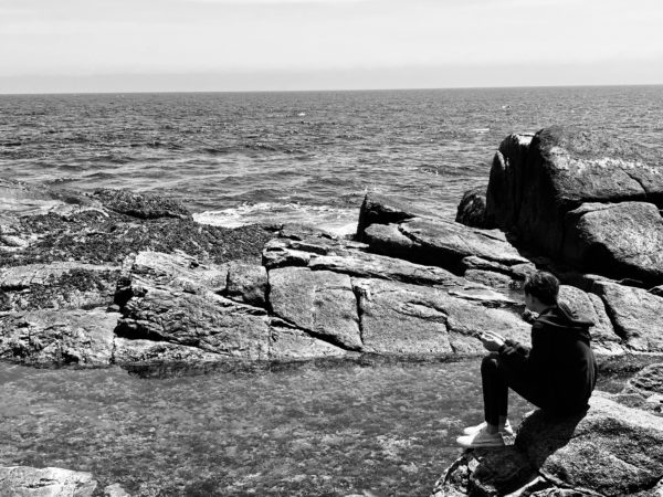 a man sitting on a rock by the ocean