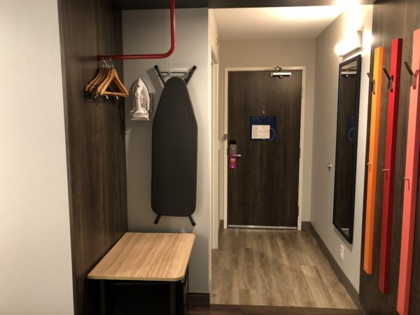 a hallway with a ironing board and a wood bench