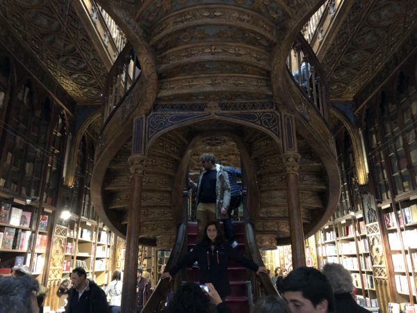 people standing on a spiral staircase in a library