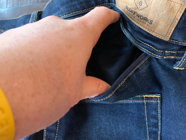a hand opening a pocket of a blue jeans