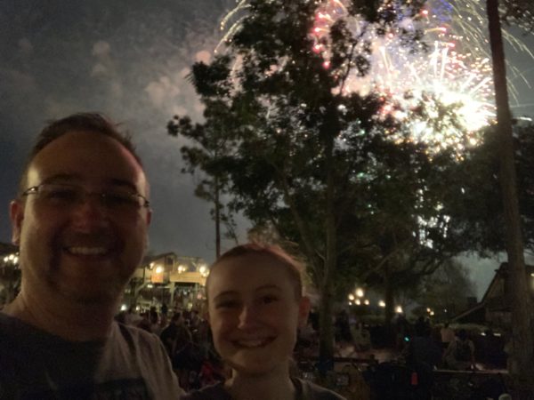 a man and woman taking a selfie in front of fireworks