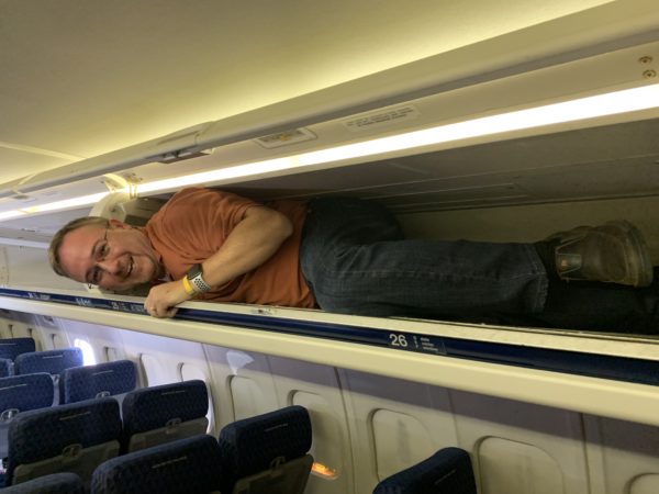 a man lying on a rail in an airplane