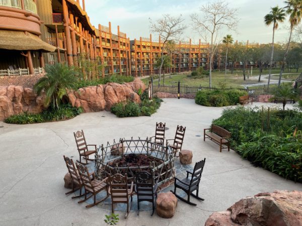 chairs around a fire pit in a courtyard with a building in the background