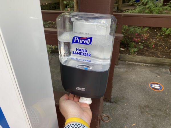 a hand holding a hand sanitizer dispenser
