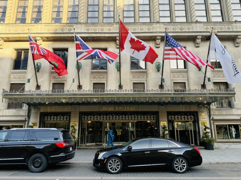 a black car parked in front of a building with flags